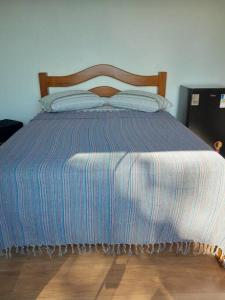 1 cama con edredón azul y almohadas en Por de sol no mar da cama, en Caraguatatuba