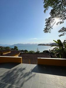 2 panche sedute su un patio con vista sull'acqua di Por de sol no mar da cama a Caraguatatuba