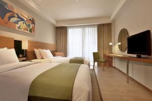 a hotel room with two beds and a flat screen tv at Diamond Hotel Kuta Bali in Kuta