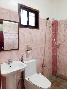 a pink bathroom with a toilet and a sink at Woodland Inn in El Nido