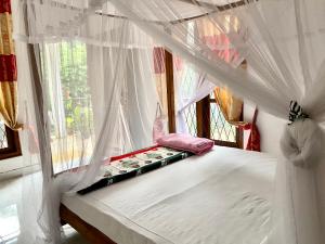 a bedroom with a canopy bed with a window at Mama Cottage Ella in Ella