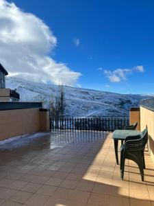 un patio con 2 sillas, una mesa y montañas cubiertas de nieve en GINEBRA CON TERRAZA, en Sierra Nevada