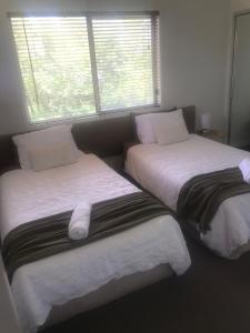 dos camas sentadas una al lado de la otra en un dormitorio en Water View Country Cottage, en Yandina Creek