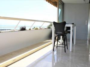 a black chair sitting at a white table in front of a window at Superbe 3 Pièces avec Terrasse, Clim et Vue Mer à Villeneuve-Loubet - FR-1-252A-92 in Villeneuve-Loubet +16 photos