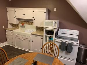 cocina con armarios blancos, mesa y microondas en Pope House - Hist. Mansion - The Green Suite, en Helena