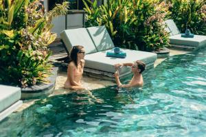 a man and a woman sitting in a swimming pool at Trawangan Dive Resort in Gili Trawangan