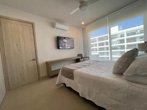 a bedroom with a bed and a tv and a window at Apartamento de Lujo, Mejor Zona de Cartagena, Manzanillo del Mar y Playa. in Cartagena de Indias