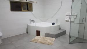 a white bathroom with a tub and a glass shower at The Winford Boutique Hotel Airport in Accra