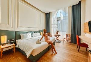 uma mulher sentada numa cama num quarto de hotel em Grand Lord Hotel & Residence em Praia de Jomtien