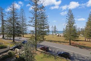a street with cars parked on the side of a road with trees at Taranaki Penthouse - wonderful in Port Macquarie