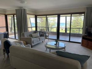 a living room with couches and a table and a television at Taranaki Penthouse - wonderful in Port Macquarie