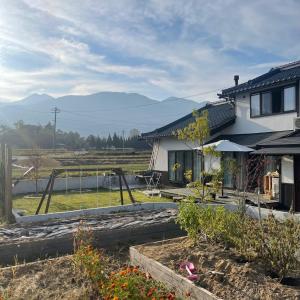 una casa con un jardín con montañas en el fondo en Azumino Fukuro Guesthouse - Vacation STAY 27117v, en Azumino