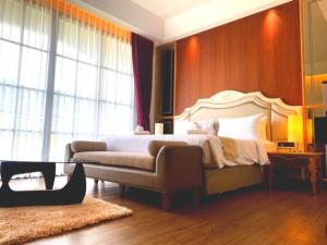 a bedroom with a bed and a couch in it at Grand Lord Hotel & Residence in Na Jomtien