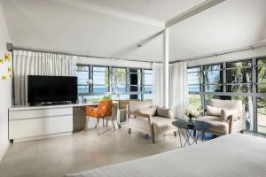 1 dormitorio con TV y sala de estar en Mangrove Hotel, en Broome