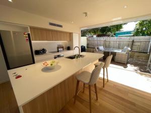 a kitchen with a white counter and chairs and a patio at Noahs Beach House - at Flynns in Port Macquarie