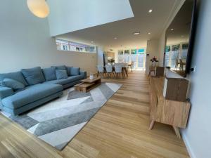 a living room with a blue couch and a table at Noahs Beach House - at Flynns in Port Macquarie