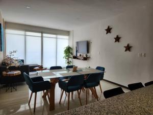 a dining room with a table and blue chairs at OLEA Beach Condos en Chicxulub Puerto in Chicxulub
