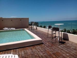 a deck with a pool and chairs and a table at OLEA Beach Condos en Chicxulub Puerto in Chicxulub