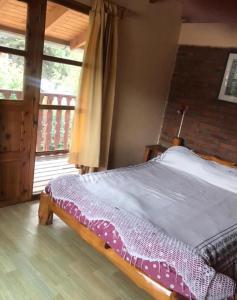 a bedroom with a bed and a window and a balcony at Cabaña familiar en pleno centro de Bolsón para 5-6 personas in El Bolsón