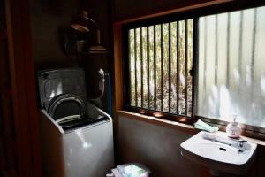 a bathroom with a sink and a window and a toilet at 佐渡島に残る築130年の伝統的な古民家｜東夢 in Sado