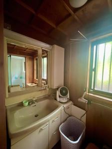 a bathroom with a sink and a mirror and a window at 佐渡島に残る築130年の伝統的な古民家｜東夢 in Sado