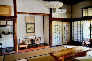 a living room with a table and some windows at 佐渡島に残る築130年の伝統的な古民家｜東夢 in Sado