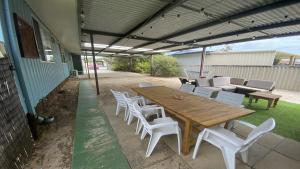 un patio con mesa de madera y sillas blancas en Eleven, en Jurien Bay