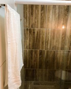 ducha con pared de madera y toalla en Tatu Suítes, en Porto de Pedras