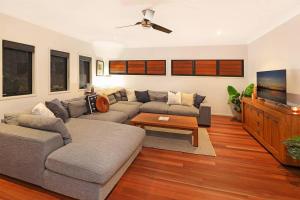 a living room with a couch and a tv at Luxury Holiday Home in Alex - Heated Pool - Pets Allowed in Alexandra Headland