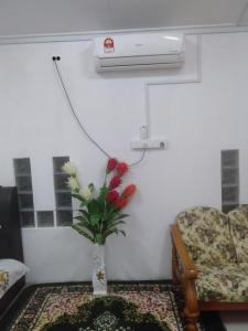 a vase with flowers in a room with a couch at Layya Homestay in Pasir Mas