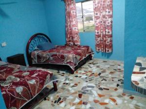 um quarto azul com duas camas e uma janela em Quinta las golondrinas em Morelos