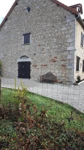 um velho edifício de pedra com uma cerca em frente em Maison Galloise em Auzances