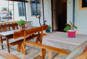 a wooden bench and table on a porch with potted plants at Horlina’s Homestay in Basco