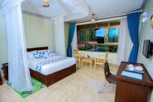 una camera con letto, scrivania e tavolo di Victoria View Boutique Hotels Kigo a Entebbe