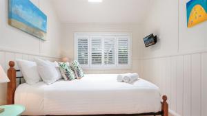 a bedroom with a white bed with pillows and a window at The Old School House in Currarong