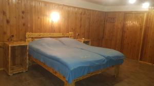 uma cama num quarto com paredes com painéis de madeira em ECO guest house em Berd
