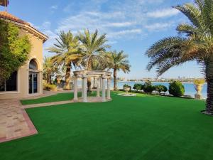a yard with a green lawn with a gazebo at Palm's Largest Beachfront Estate in Dubai