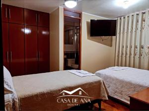 two beds in a room with a tv and a bedroom at Hostal Casa de Ana in Nazca