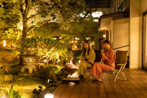 zwei Frauen sitzen um ein Feuer auf einer Terrasse herum in der Unterkunft Hotel Hoho "A hotel overlooking the Echigo Plain and the Yahiko mountain range" formerly Hotel Oohashi Yakata-no-Yu in Niigata