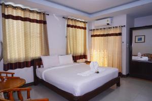 a bedroom with a large white bed with curtains and a sink at Tamnak Lanta @Chiang Mai in Chiang Mai