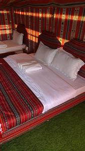 ein großes Bett in einem Zimmer mit roten und eingeschnittenen Wänden in der Unterkunft Sunrise Desert Local Private Camp in Badīyah