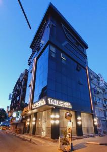 een hoog gebouw met een bord ervoor bij TALLES CITY HOTEL in Konak