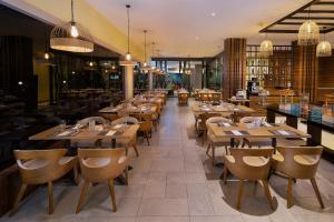 un restaurante con mesas de madera y sillas en una habitación en Swiss-Belinn Baloi Batam en Nagoya