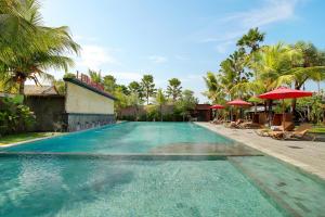 a swimming pool with chairs and umbrellas in a resort at Lumbini Luxury Villas and Spa in Jimbaran