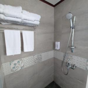 a bathroom with a shower and towels on a wall at Xian Jing B&B in Jiaoxi