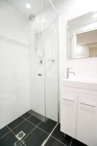 ein weißes Bad mit einer Dusche und einem Waschbecken in der Unterkunft CBD #UnitA Grennland6 1 bedroom apt Darling Harbour in Sydney