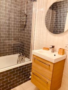 La salle de bains est pourvue d'un lavabo, d'une baignoire et d'un miroir. dans l'établissement Le Bohème Parking Proche Centre, à Châteauroux