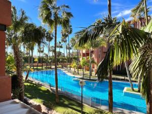 Blick auf einen Pool mit Palmen in der Unterkunft PUSHE Playa Granada Beach & Golf 11 in Motril