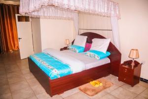 a bedroom with a large wooden bed with blue pillows at Light House Hotel in Huye
