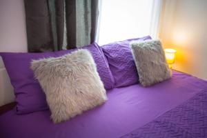 2 cuscini su un letto viola con finestra di Apartmani Remete a Zagabria